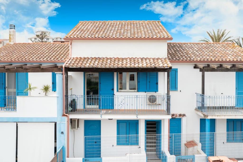 a white house with blue shutters at Casa Vacanza sotto torre in Calasetta