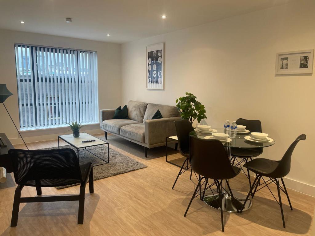 uma sala de estar com um sofá, uma mesa e cadeiras em stylish modern one bed Apartment em Birmingham