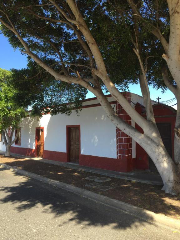 una casa roja y blanca con un árbol al lado en GBH Casa Quintana, en La Oliva