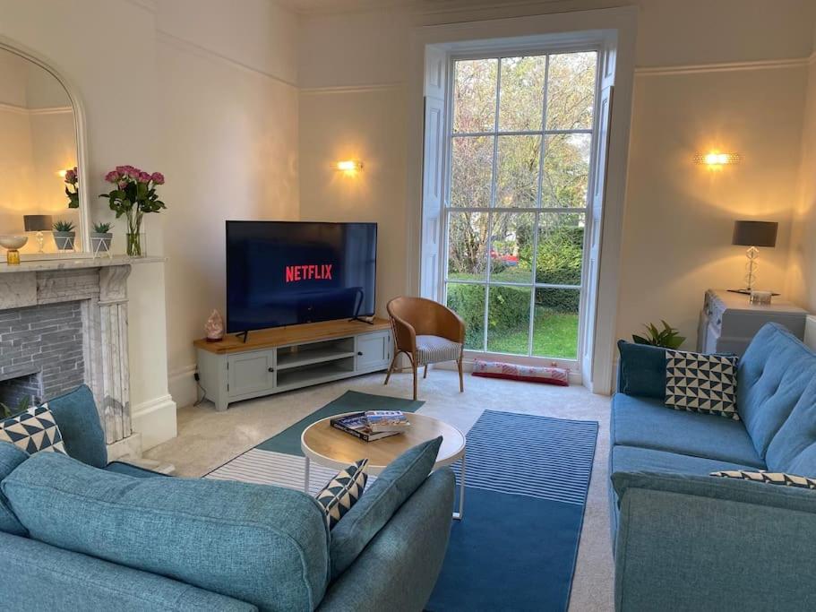 a living room with blue couches and a tv at Regency Apartment in Leamington Spa