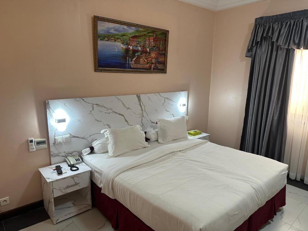 - une chambre avec un grand lit et une tête de lit en marbre dans l'établissement Hotel Fleur De Lys Almadies, à Dakar