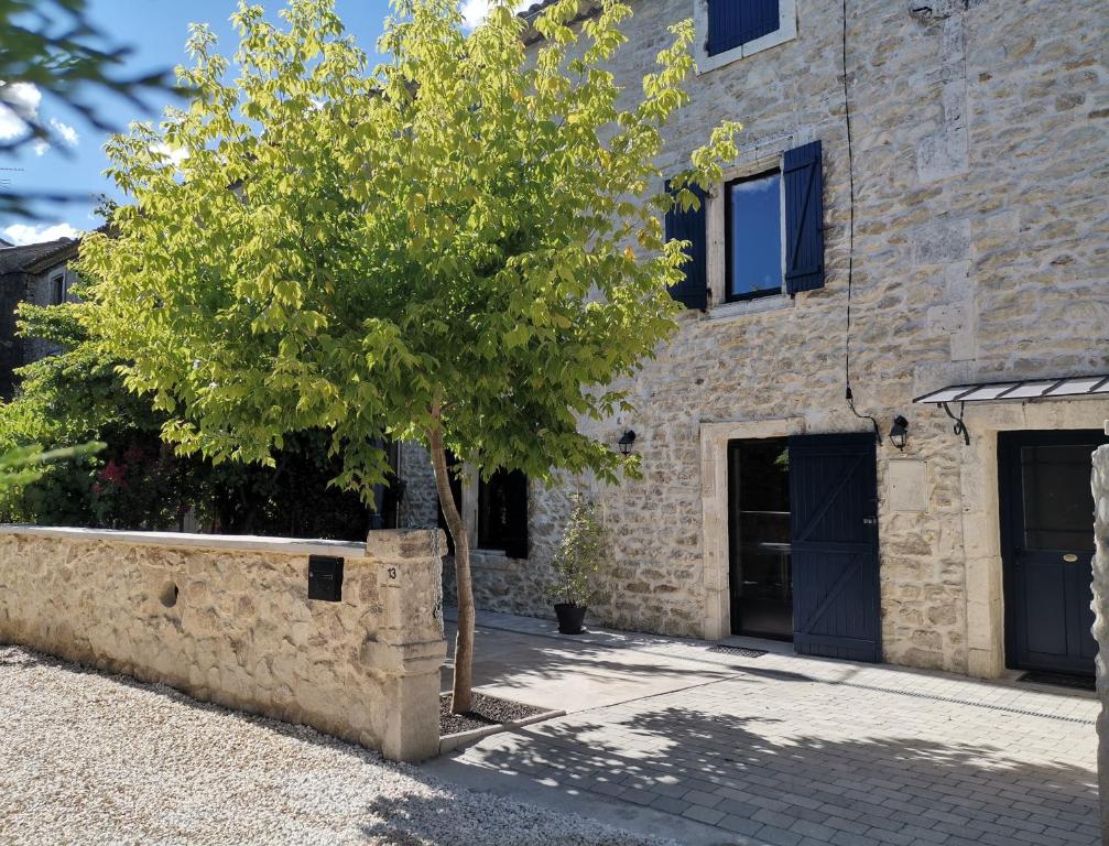 a tree in front of a stone building at Namaste Home, charming holiday home in Saint Rémy de Provence - South of France in Saint-Rémy-de-Provence