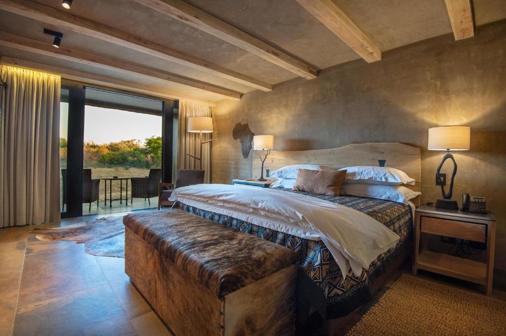 - une chambre avec un grand lit et une grande fenêtre dans l'établissement Kapama River Lodge, à Réserve privée de Kapama