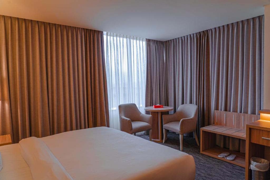 um quarto de hotel com uma cama, uma mesa e cadeiras em La Casa Hotel Amman by FHM em Amã
