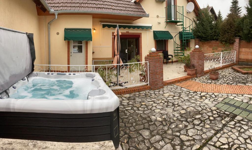 uma banheira de hidromassagem num quintal em frente a uma casa em Amerikai Álom em Orfű