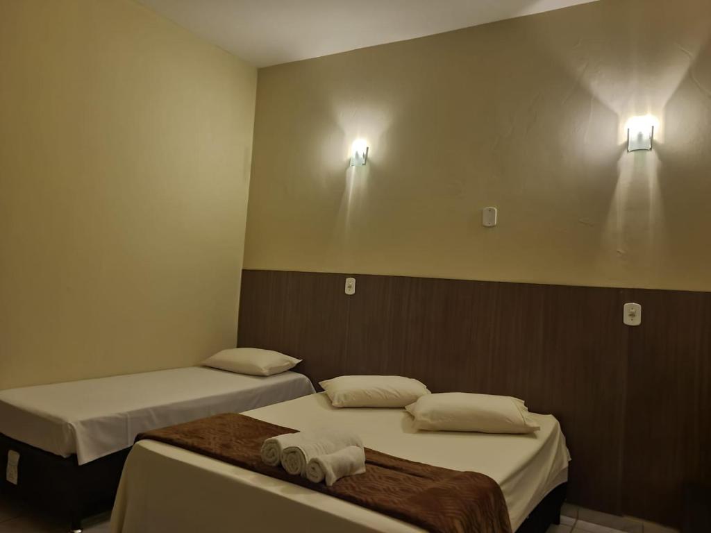 博尼圖的住宿－Pousada Rancho Bonito，两张床位于带两盏灯的墙上。