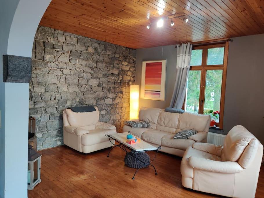 una sala de estar con 2 sofás y una pared de piedra. en Appartement cosy à Chimay, en Chimay