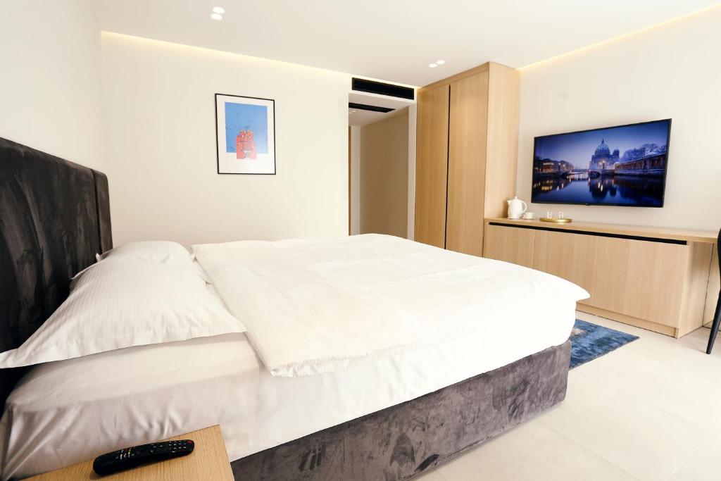 a bedroom with a large white bed and a tv at HOTEL 12 in Gjakove