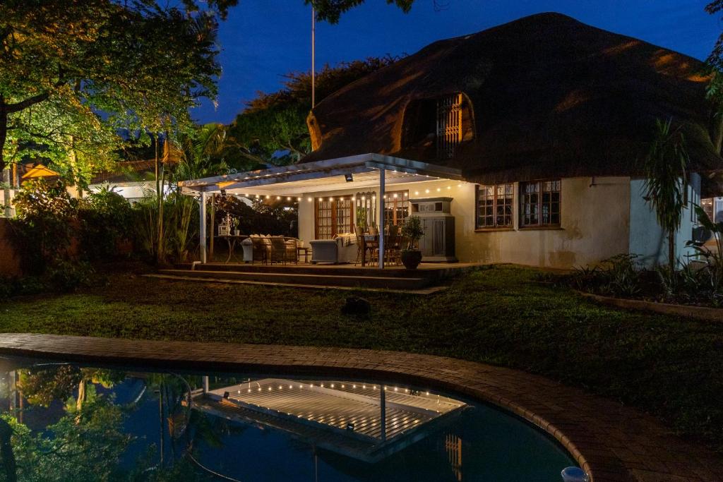 a house with a thatched roof and a pool at 30 Mimosa in Mtunzini