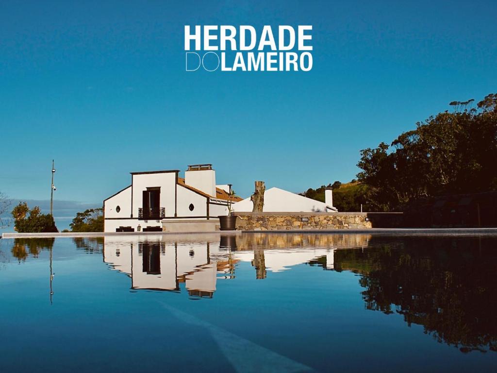 un edificio con la sua riflessione in un corpo idrico di Herdade do Lameiro - Turismo Rural a Ribeira Grande