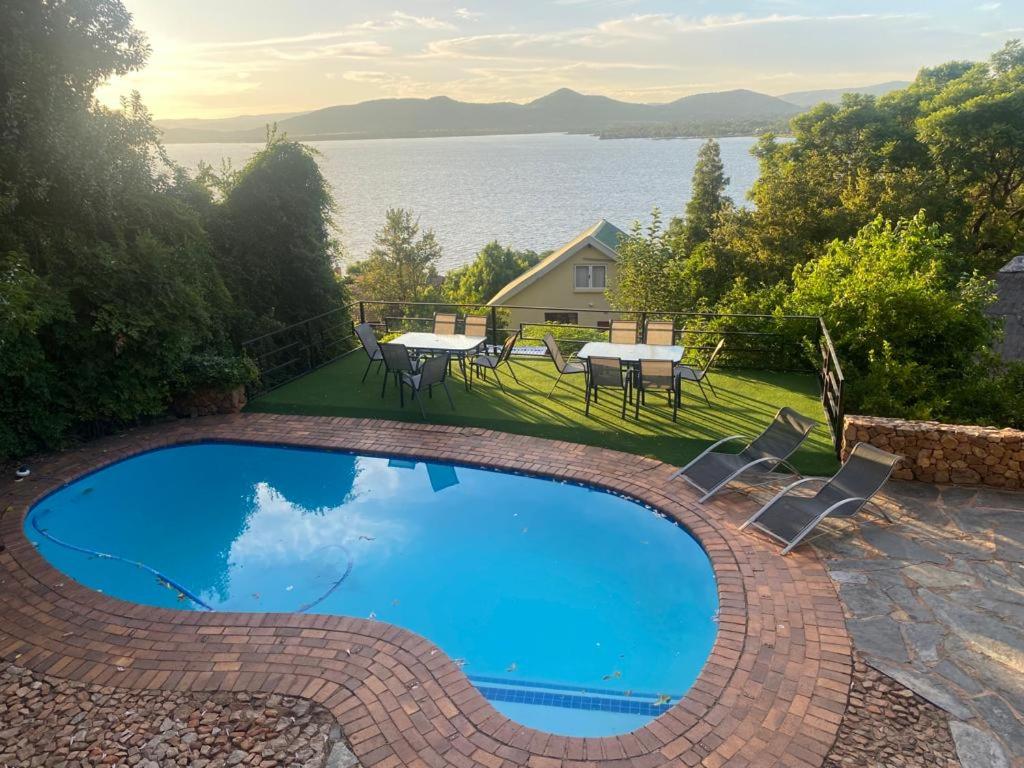 Manz' amahle Guest Cottage في هارتبيسبورت: مسبح ازرق كبير مع كراسي وطاولة