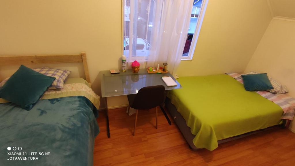 sypialnia z 2 łóżkami, biurkiem i stołem w obiekcie Casita de Sara w mieście Castro