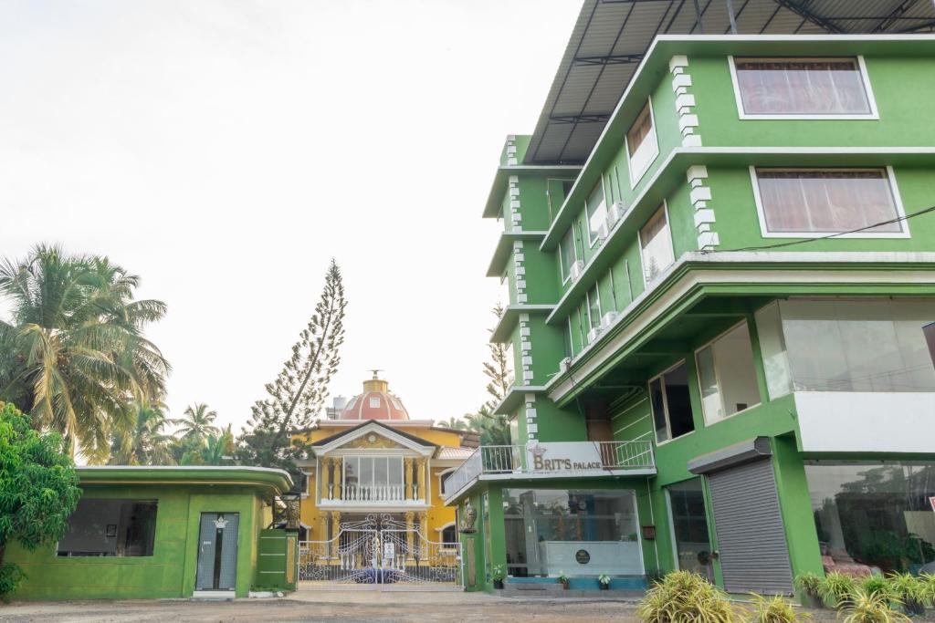 um edifício verde com uma casa ao fundo em Brit's Palace Goa em Agacaim