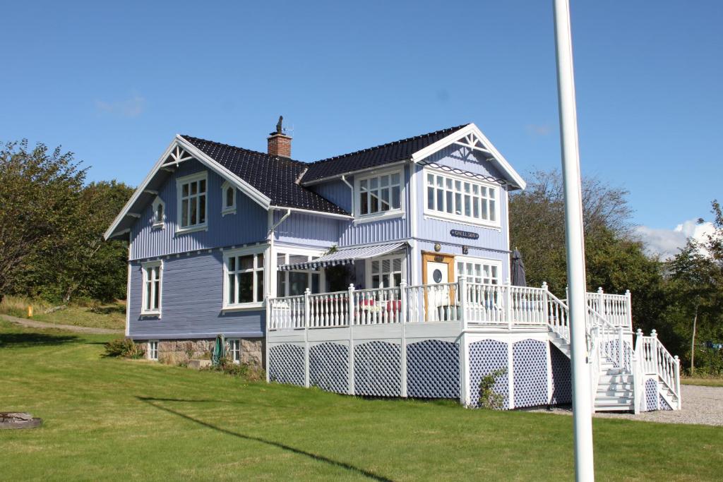 uma grande casa azul com um alpendre branco em Grellsbo em Grebbestad