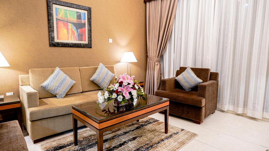 a living room with a couch and a table with flowers on it at Xclusive Hotel Apartments in Dubai