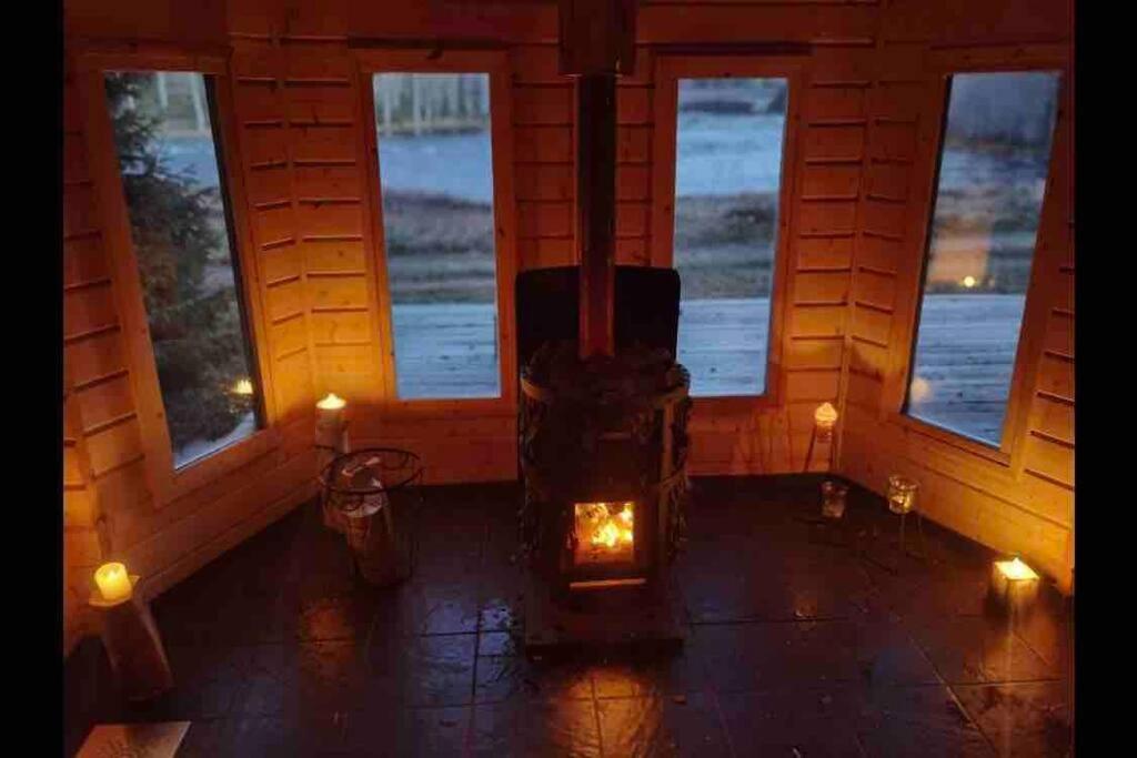 a room with a wood stove in a room with windows at Lovely cabin with a beautiful view over Byske river in Byske