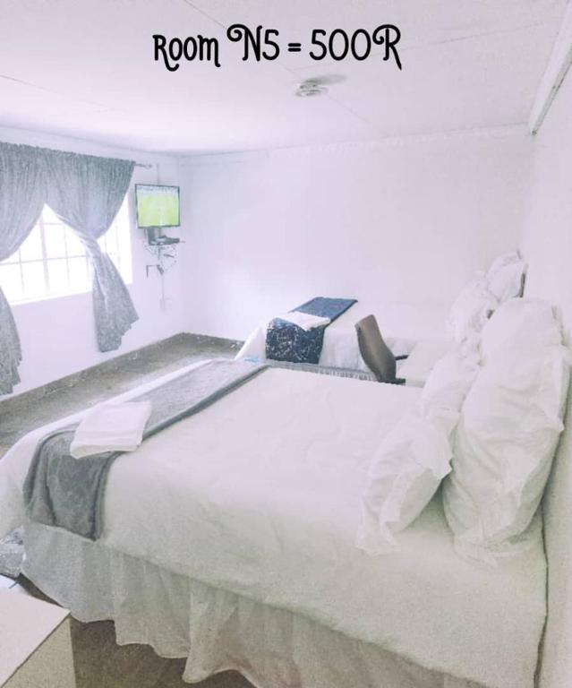 a bedroom with a large white bed in a room ms at PRIME GUEST HOUSE in Boksburg