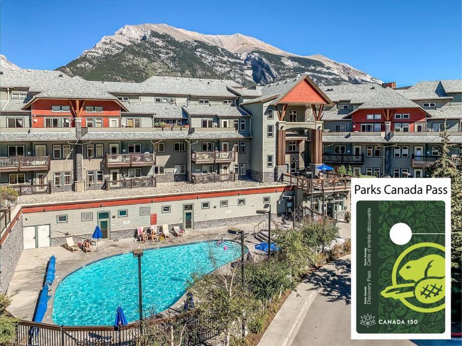 a resort with a swimming pool in front of a mountain at Mountain Retreat - Modern and Bright with Panorama Views 2 bedrooms, 4 beds, heated all-year outdoor pool, hottub, balcony, Banff Park Pass in Canmore