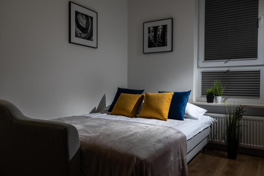 - une chambre avec un lit doté d'oreillers jaunes et bleus dans l'établissement ResiNest Apartamenty Kopernik, à Białystok