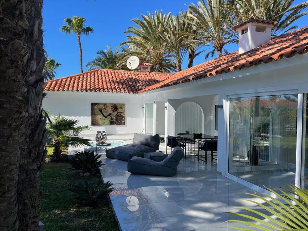 eine Terrasse eines Hauses mit einem Sofa und Stühlen in der Unterkunft Sun Club Luxus Bungalow Projecto 65 in Maspalomas