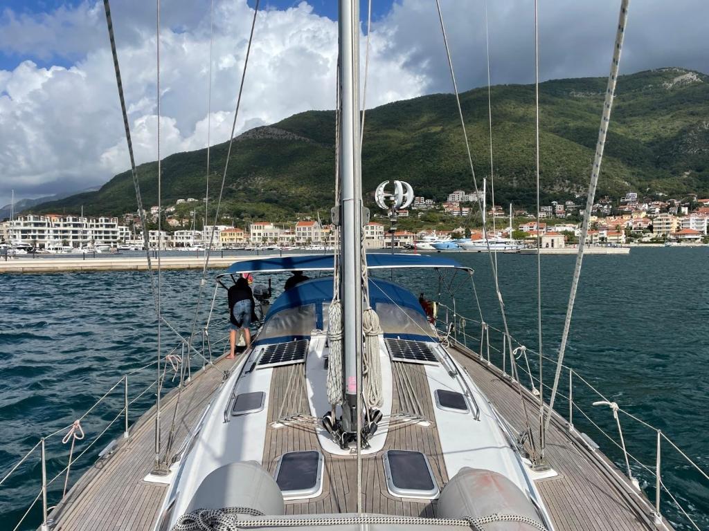 a sailboat in the water with a city in the background at Yachthafen Marina Bar in Herceg-Novi