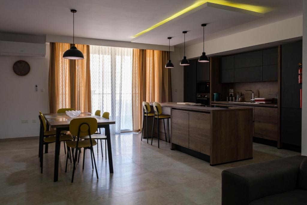 Modern 3 bedroom Apartment in Luqa (Sleeps 6) في لوكا: مطبخ وغرفة طعام مع طاولة وكراسي