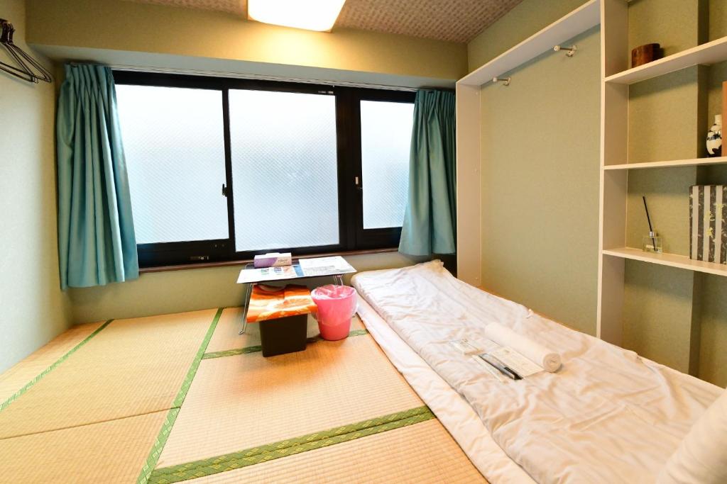 um quarto com uma cama e uma grande janela em Jing House akihabara Ryokan - Vacation STAY 11566v em Tóquio