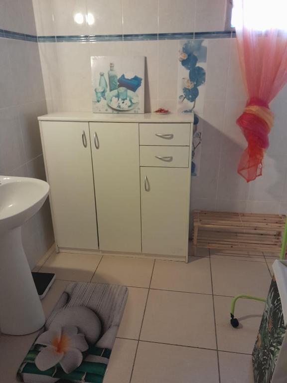 a bathroom with a sink and a white cabinet at Un petit coin de Paradis in Deshaies
