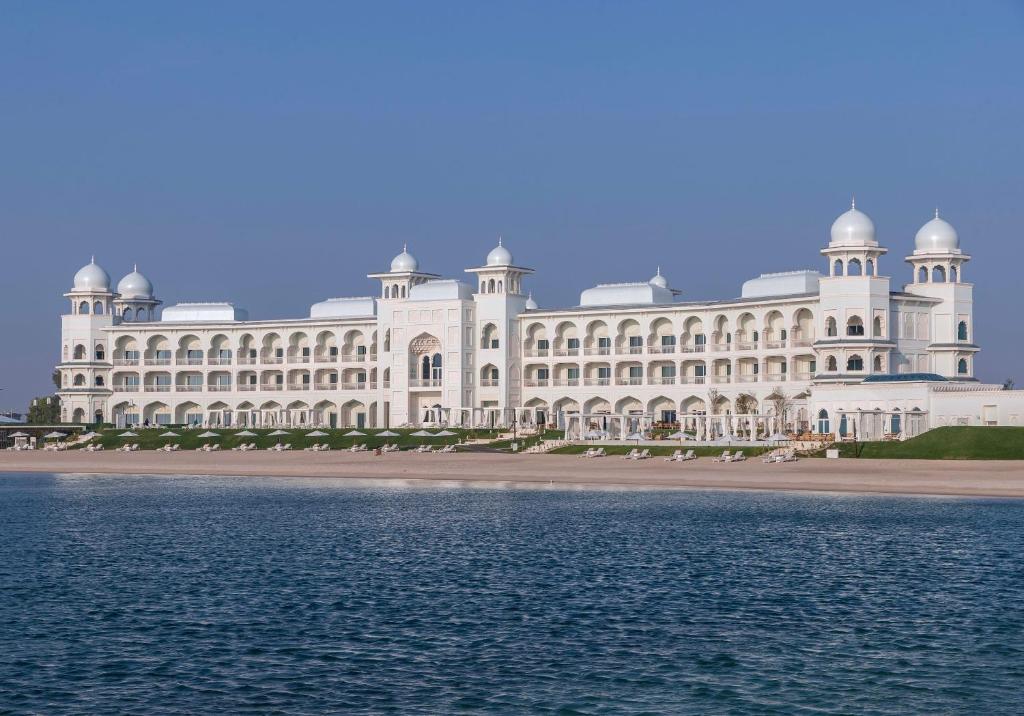 a large white building next to a body of water at The Chedi Katara Hotel & Resort in Doha