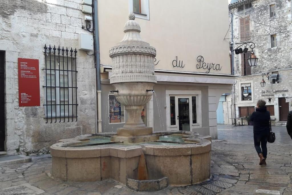 Une femme qui passe devant une fontaine dans une rue dans l'établissement Studio dans cité historique wifi et vue magnifique, à Vence