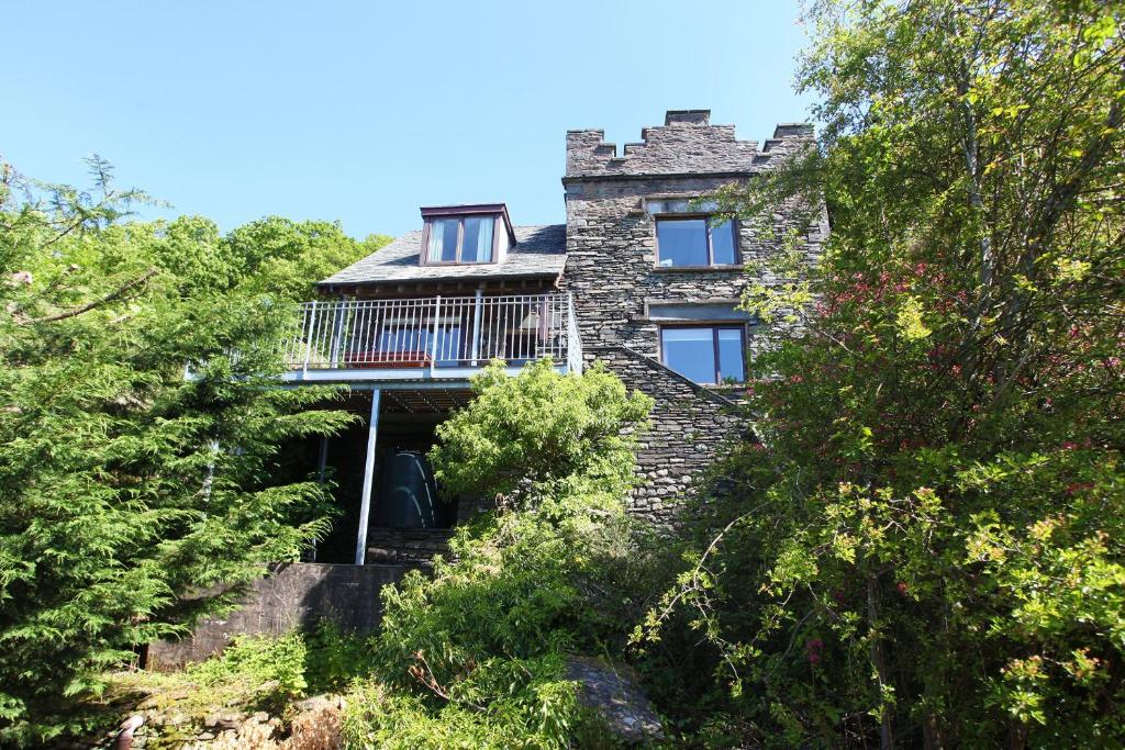 uma antiga casa de pedra com uma varanda numa colina em Tower Cottage Far Sawrey Windermere em Far Sawrey