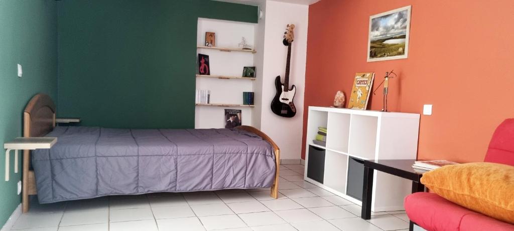 sypialnia z łóżkiem, biurkiem i gitarą w obiekcie Studio en plein coeur de Chanac w mieście Chanac