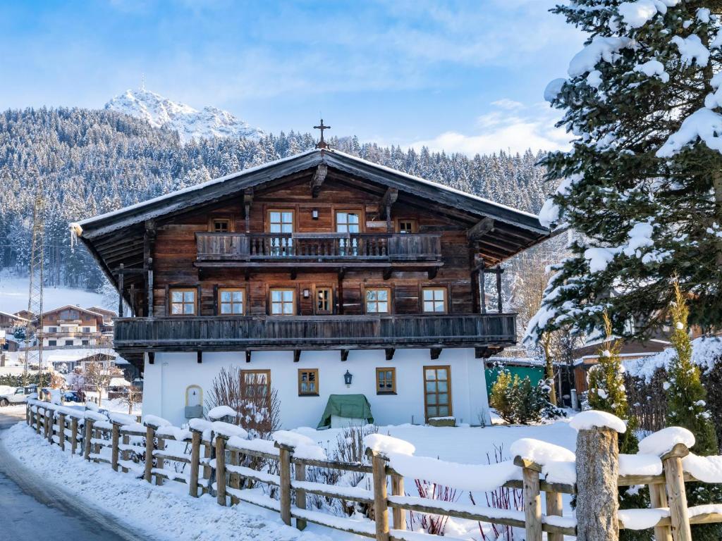 ein Blockhaus im Schnee mit einem Zaun in der Unterkunft Landhaus Ammer in Oberndorf in Tirol
