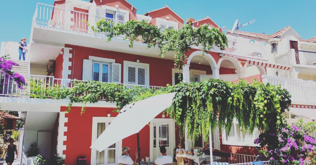 een rood-wit gebouw waar mensen voor zitten bij Villa Kipre 2 in Cavtat