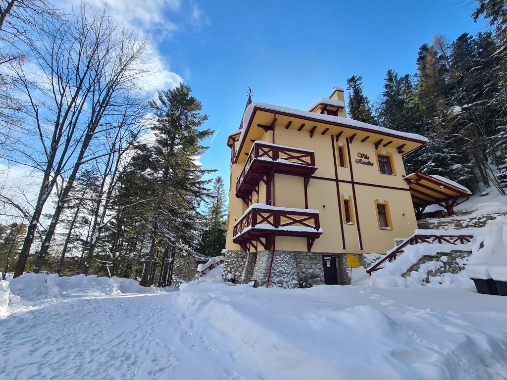 Un edificio en la nieve con nieve a su alrededor. en Villa Rusalka, en Vysoké Tatry
