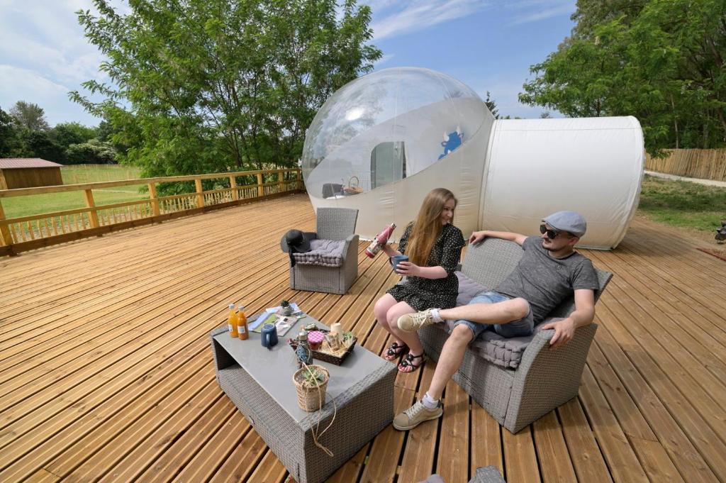 een man en vrouw op een dek met een bubbeltent bij Bulle SPA Romantique in Jarcieu