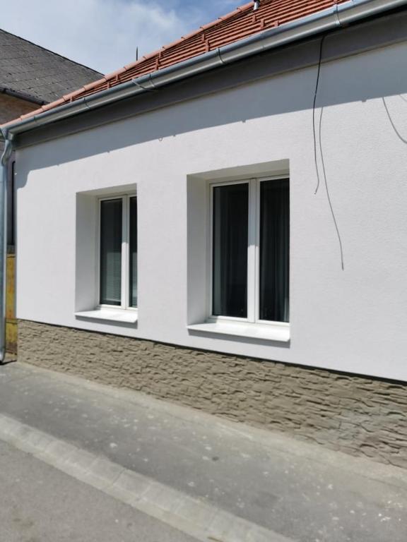 a white building with two windows on a street at Tifani Apartman in Keszthely