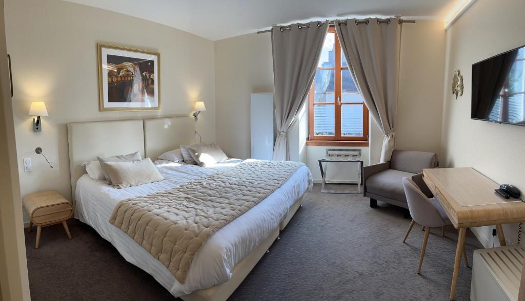 a hotel room with a large bed and a chair at Logis Hôtel des Messageries in Arbois