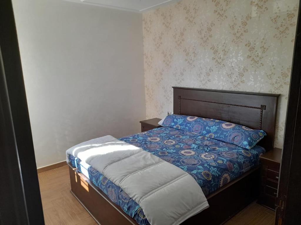 a bedroom with a bed with a blue comforter at appartement NADOR wifi gratuit in Nador