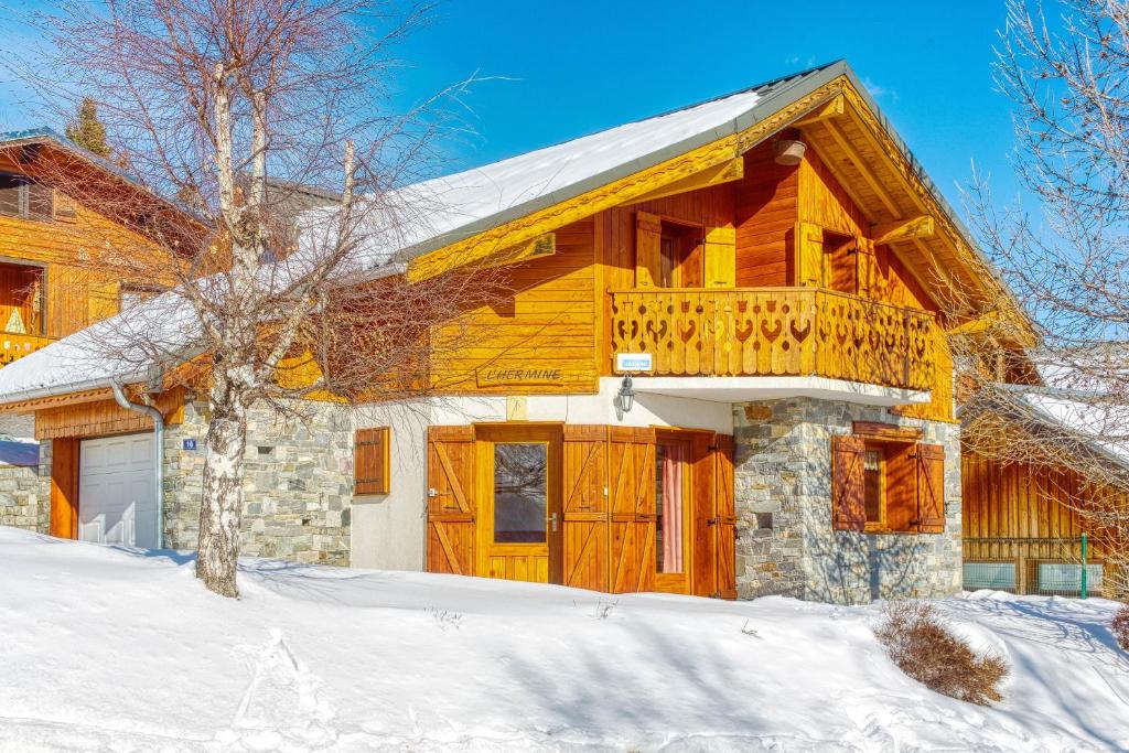 a wooden house with a balcony in the snow at Chalet l'Hermine in La Toussuire