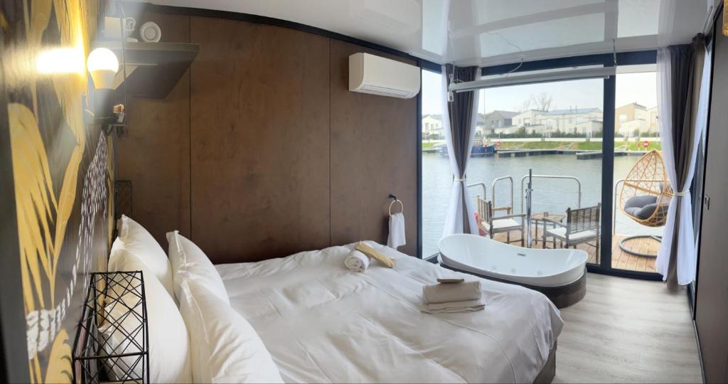 a bedroom with a bed and a tub and a balcony at L&#39;Escale Royale L&#39;Isle Adam à 20 minutes de Paris CDG in LʼIsle-Adam