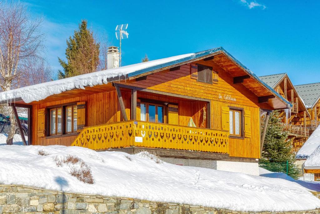 una casa de madera con una gran terraza en la nieve en Chalet les Colchiques en La Toussuire