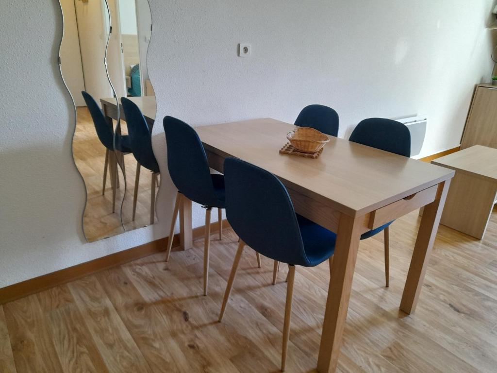 a dining room table with blue chairs and a mirror at Appartement T2 Jardins de Ramel in Luchon