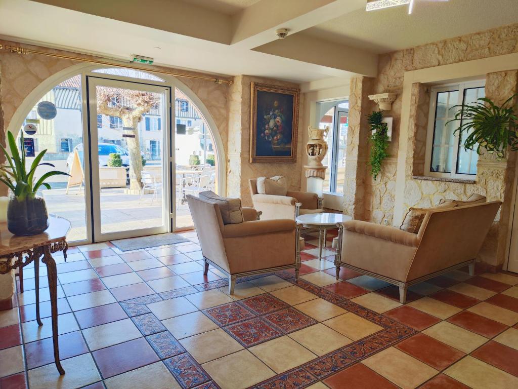 a lobby with chairs and a table in a room at Hôtel-Restaurant le Commerce in Nogaro