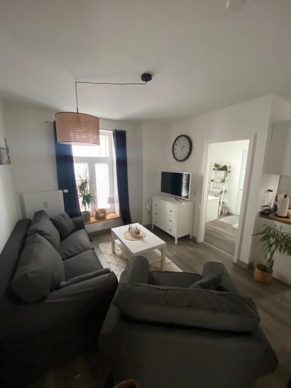 a living room with a couch and a table and a clock at FeWo Jade in Wilhelmshaven