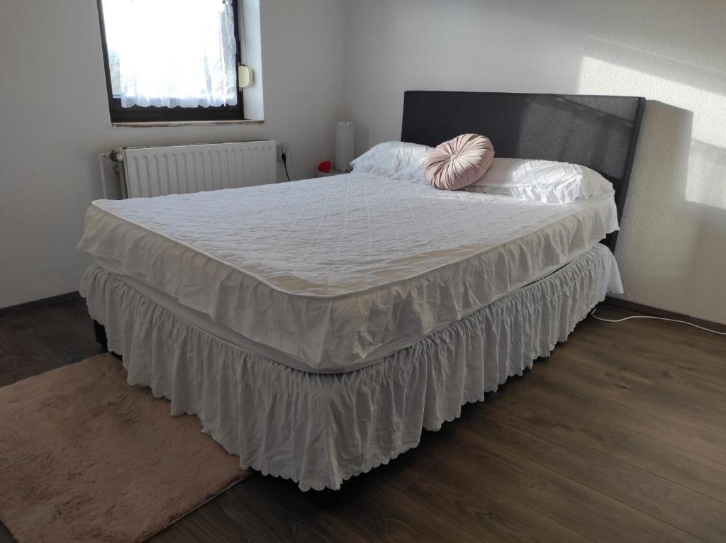 a bedroom with a large bed with white sheets and a pink pillow at Apartment am See - Borken, Hessen in Borken