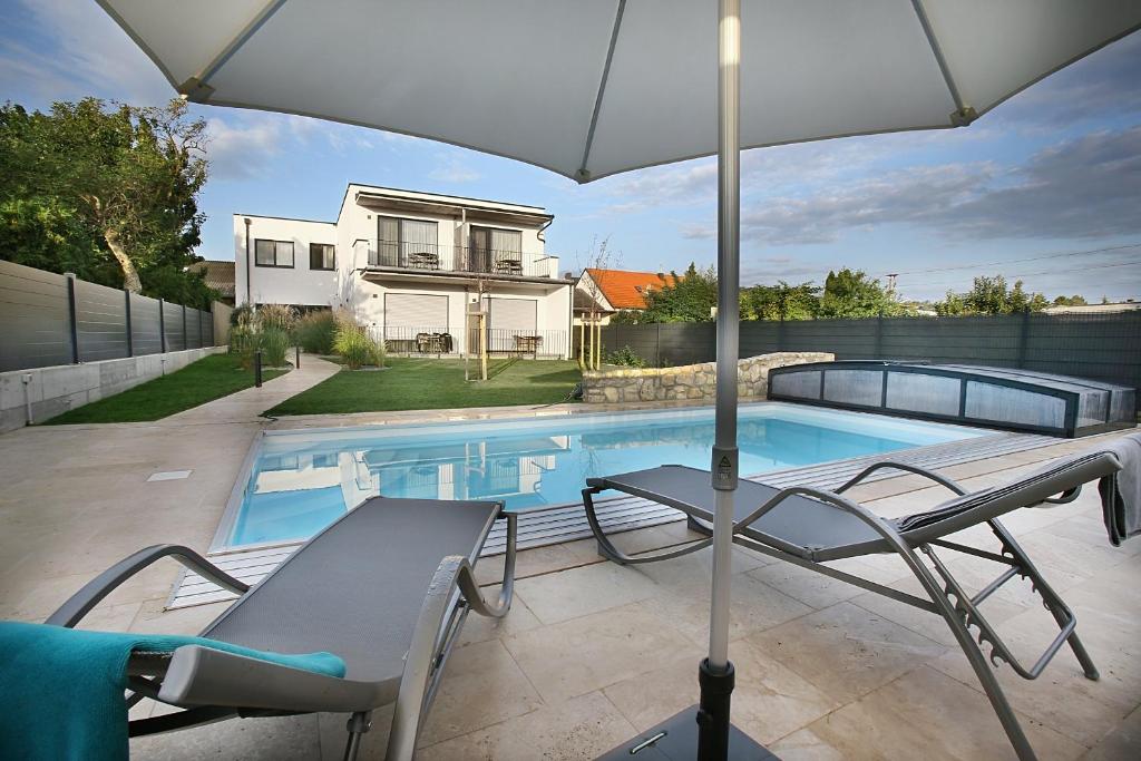 una piscina con 2 sillas y una sombrilla en Schlafgut FAM Steurer, en Jois