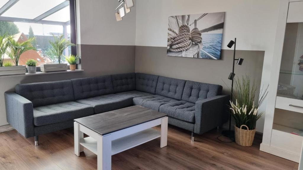 - un salon avec un canapé bleu et une table dans l'établissement Ferienhaus-Kegelrobbe, à Dornumersiel