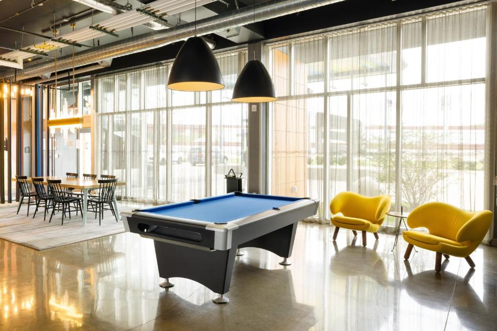 a pool table in a room with chairs and tables at Aloft Austin Airport in Austin