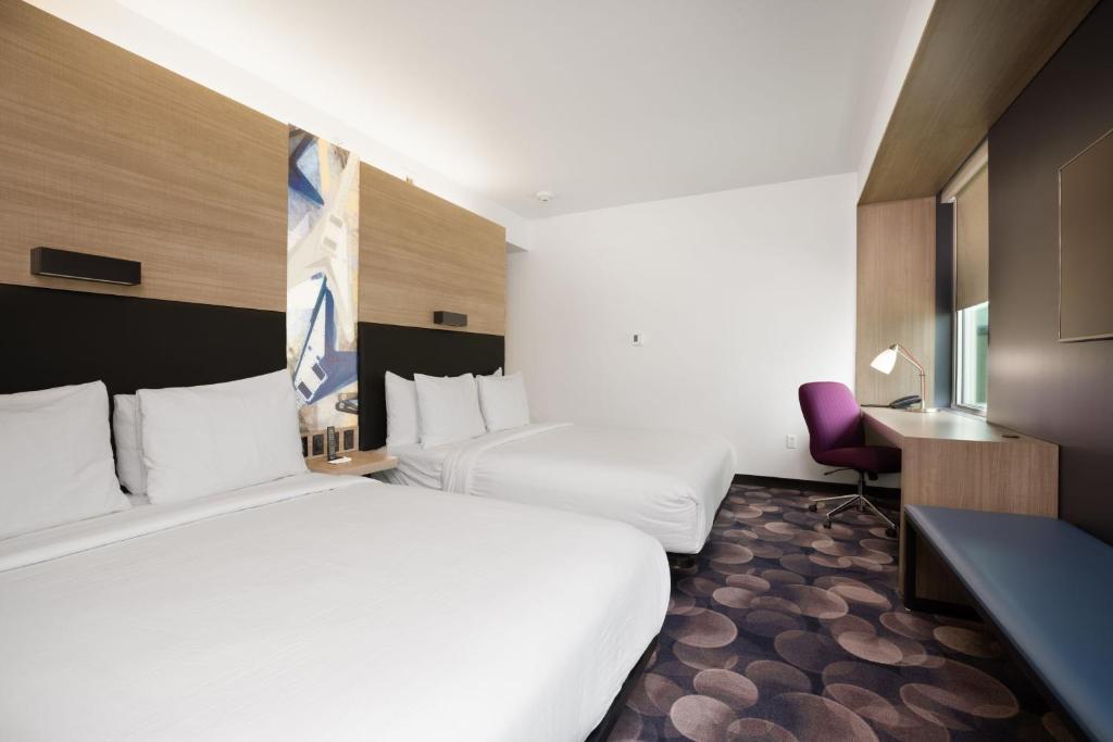 a hotel room with two beds and a chair at Aloft Austin Airport in Austin
